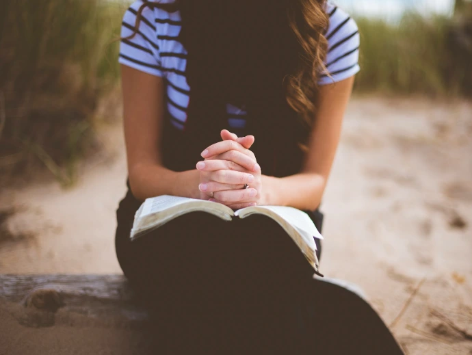 woman sitting on brown bench while reading book